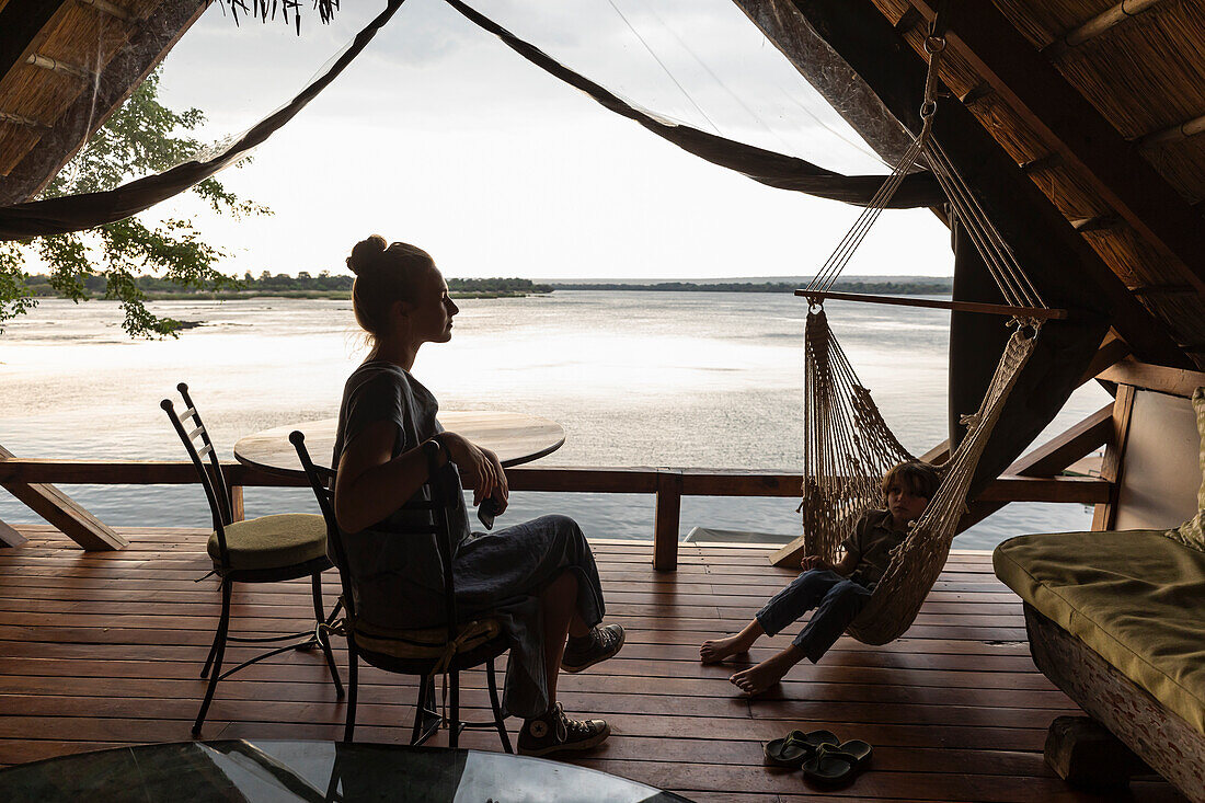 Afrika, Sambia, Livingstone, Bruder (8-9) und Schwester (16-17) entspannen in Lodge am Sambesi-Fluss