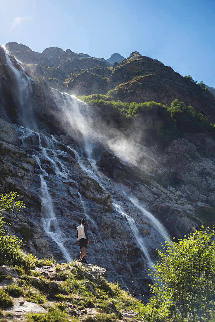 Russland, Karatschai-Tscherkessien, Arkhyz, Mann in der Nähe des Sofiyskiye Vodopady-Wasserfalls im Kaukasusgebirge