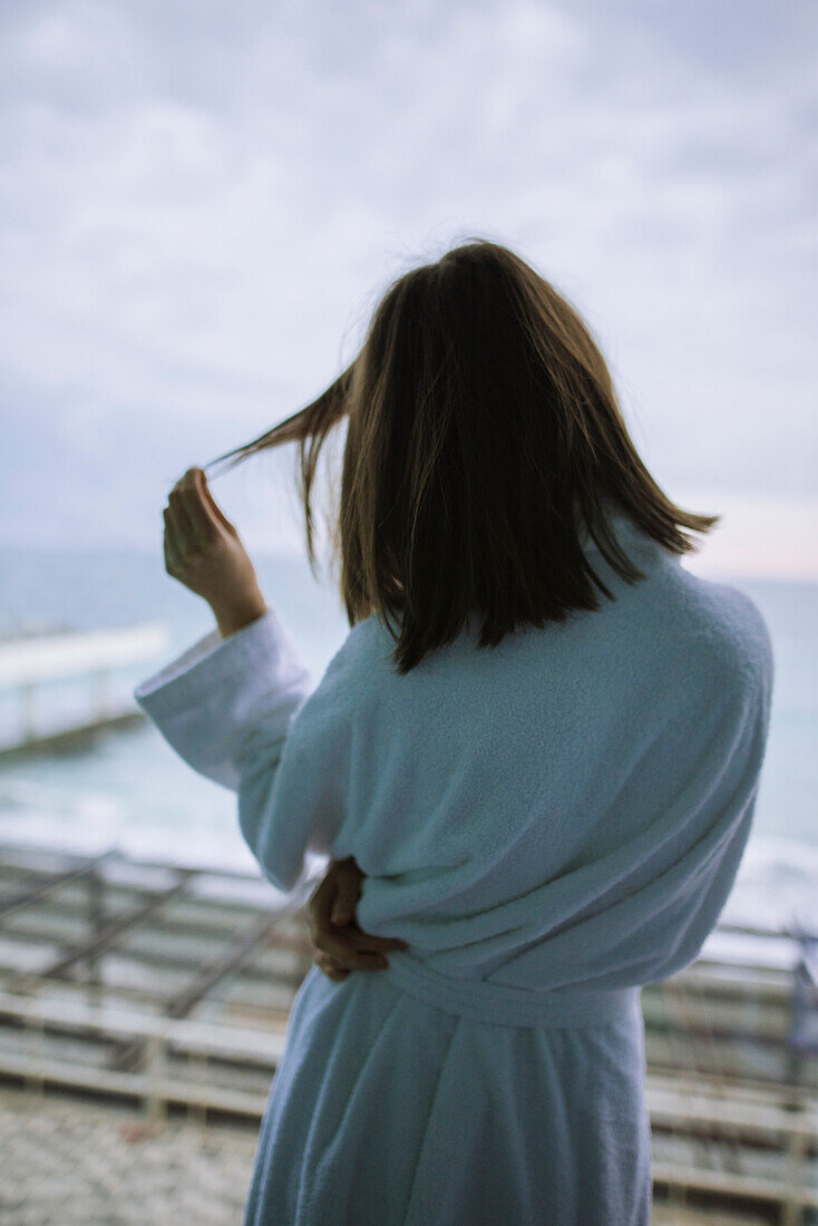 Rückansicht einer Frau im Bademantel in einem Hotel mit Blick auf das Meer