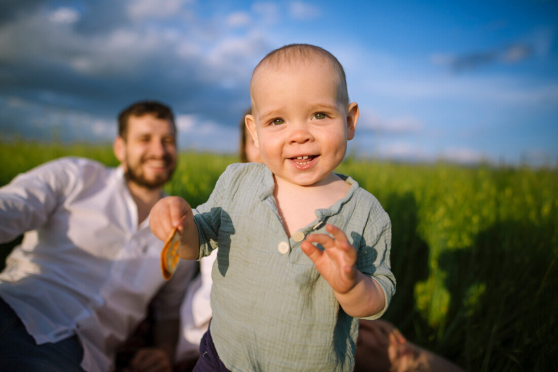 Baby boy (12-17 months) with parents in agricultural field