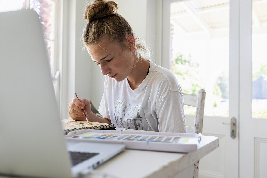 Mädchen (16-17) bei der Arbeit an einer Aquarellzeichnung im Atelier