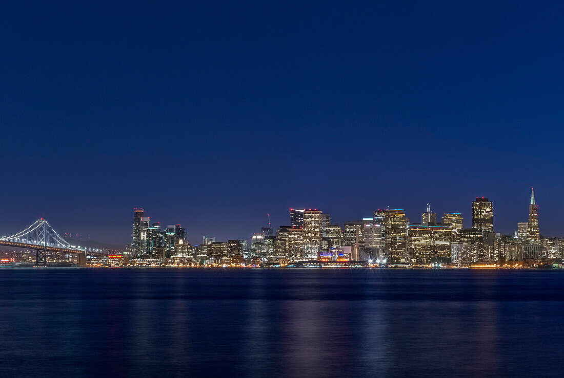 USA, Kalifornien, San Francisco, Bay Bridge und Skyline der Innenstadt in der Abenddämmerung