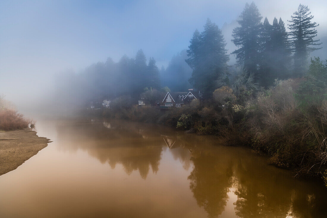 Der sich auflösende Nebel am Russian River mit den Häusern am Flussufer am frühen Morgen im Winter.