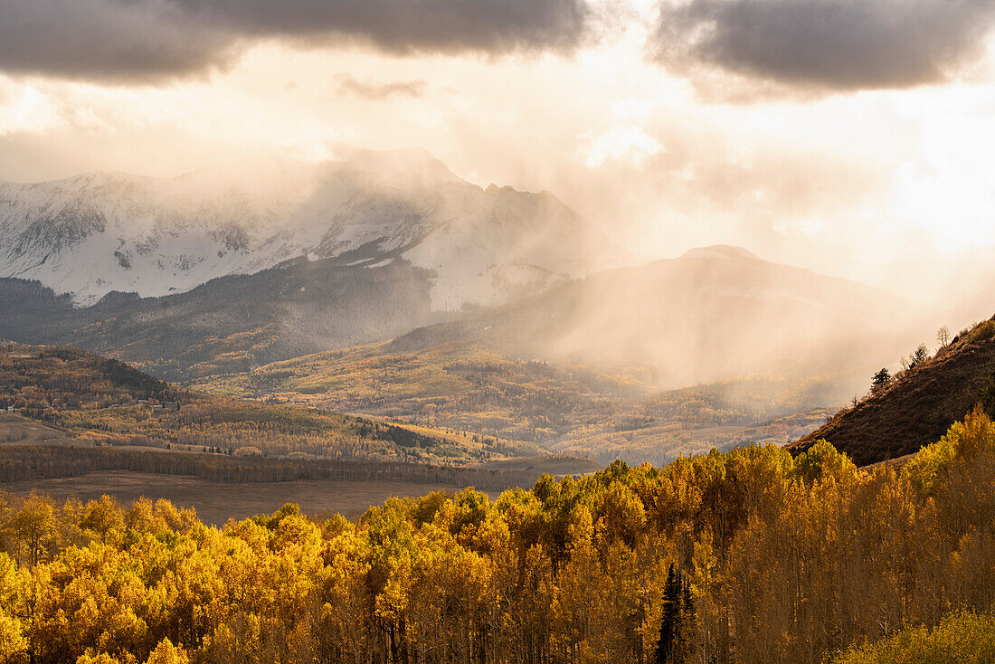 USA, Colorado, San Juan Mountains. Snow flurries over mountain and valley at sunset
