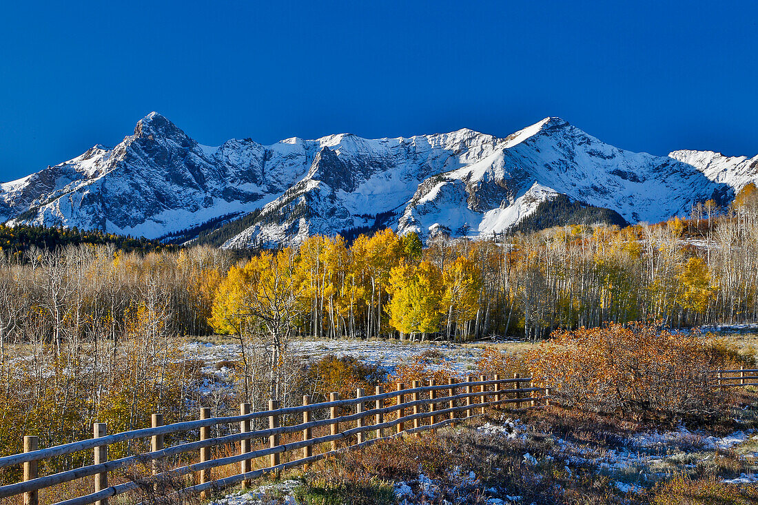 Dallas Mountain and San Juan Mountain Range, Colorado, Autumn colors and aspens glowing gold with wooden fence line