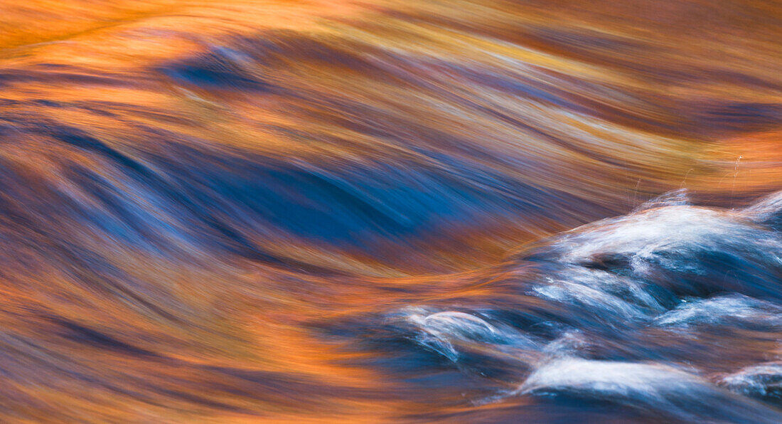 Painterly Impression of a rushing stream reflecting autumn colors.