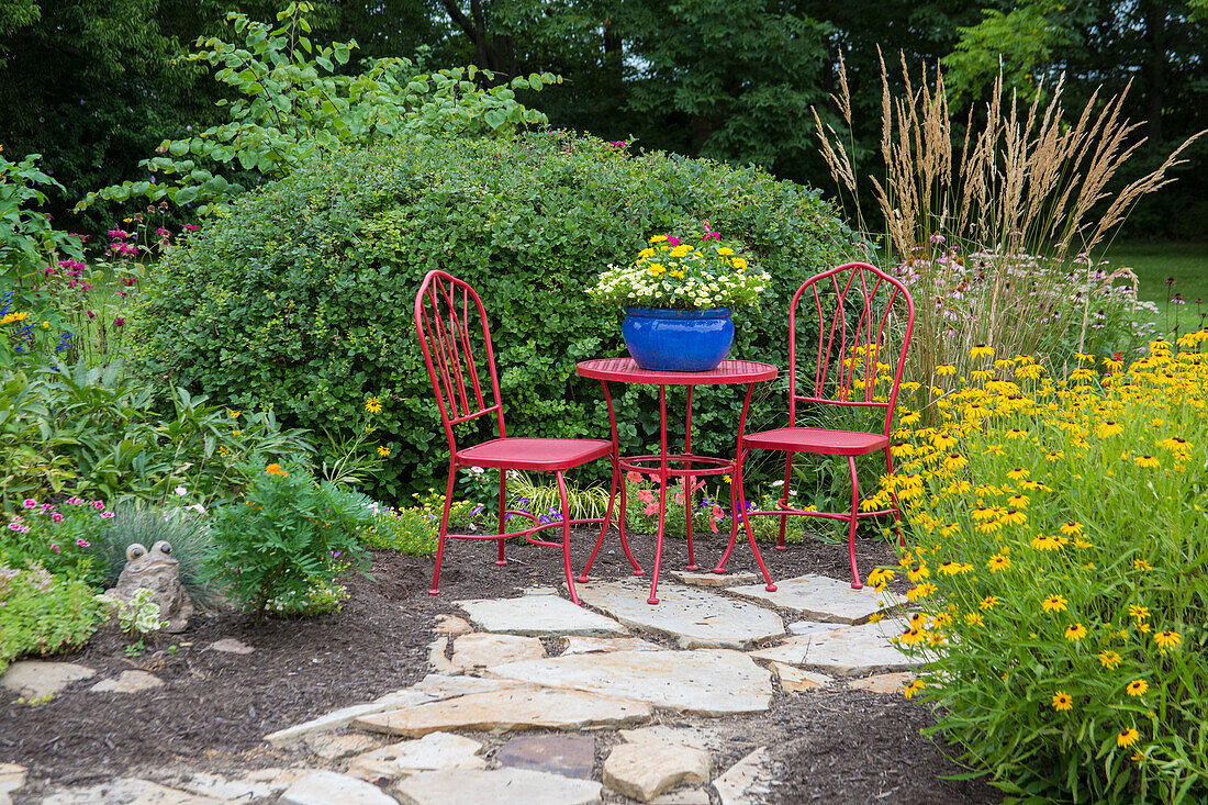 Roter Tisch und Stühle mit blauem Topf im Blumengarten. Marion Grafschaft, Illinois (PR)