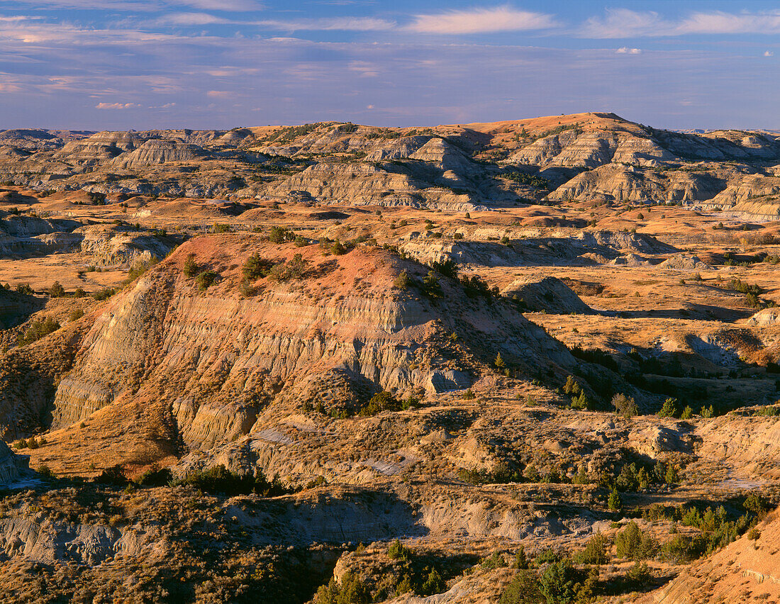 USA, North Dakota, Theodore Roosevelt National Park, Abendlicht definiert erodierte, sedimentäre Hügel und grasbewachsene Ebenen im Herbst, Painted Canyon Overlook, South Unit.