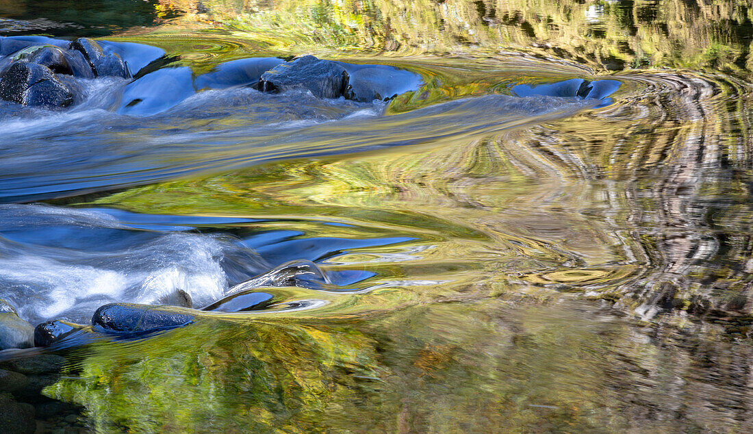 USA, Oregon. Abstrakte Herbstfarben, die sich in den Stromschnellen des Wilson River spiegeln
