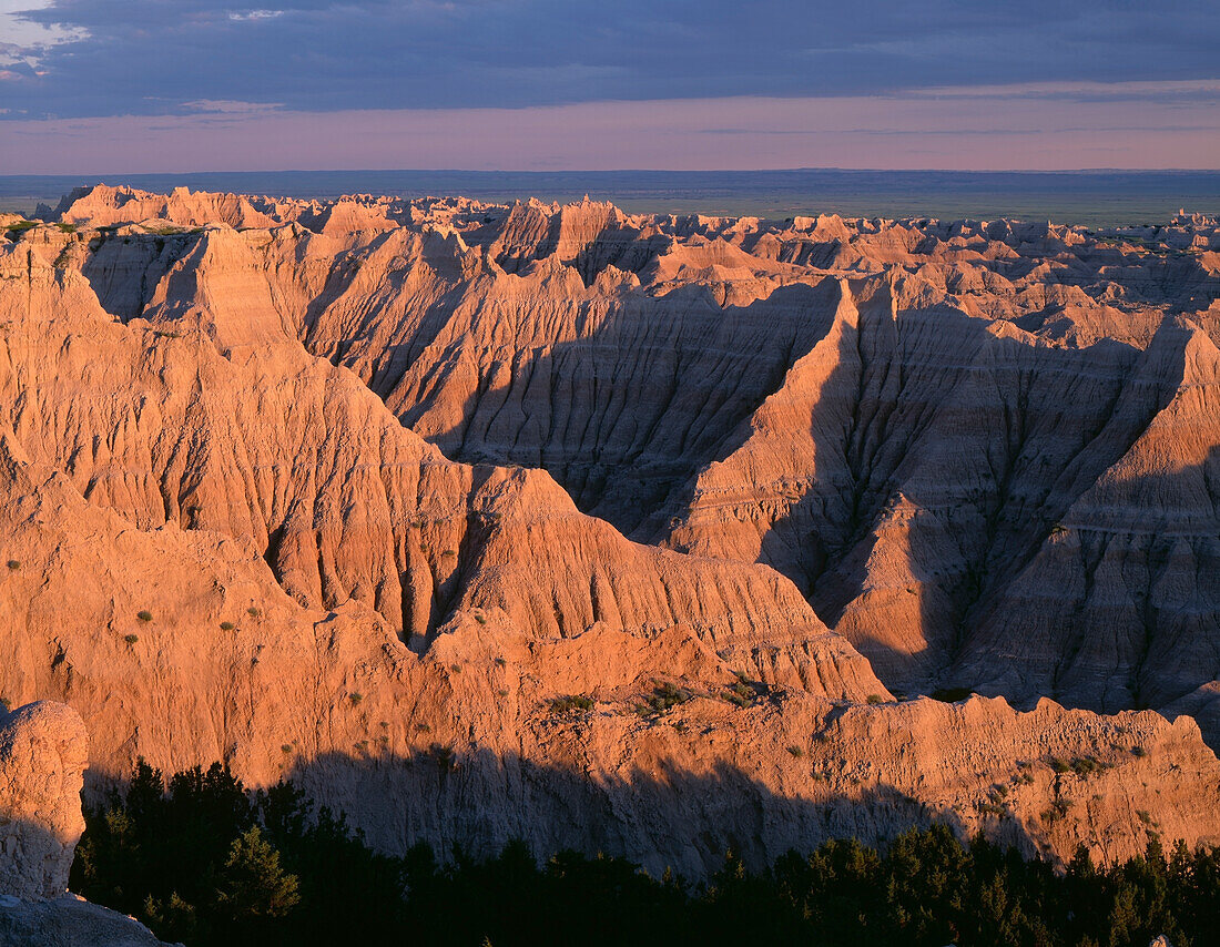 USA, South Dakota, Badlands National Park, North Unit, Sonnenuntergangslicht auf einem ausgedehnten Gebiet mit erodierten Sedimentformationen in der Nähe des Pinnacles Overlook.