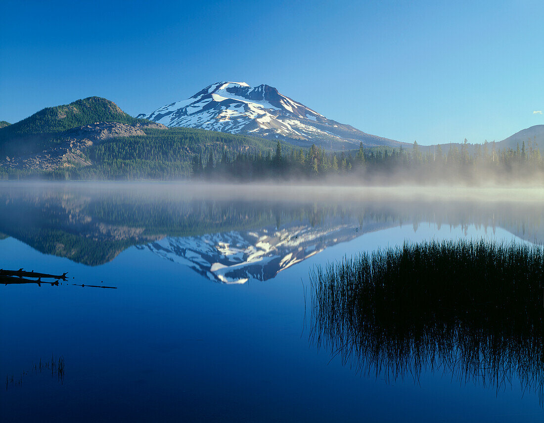 USA, Oregon, Deschutes National Forest, South Sister reflects in the misty waters of Sparks Lake in early morning.