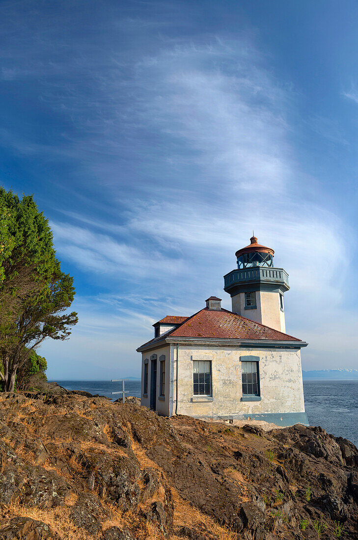 USA, Bundesstaat Washington, San Juan Island, Lime Kiln Point State Park, Lime Kiln Point Leuchtturm und felsige Küste unter einem wolkenverhangenen Himmel.