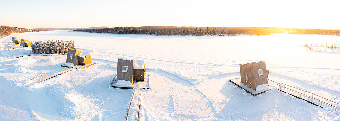 Die Holzhütten des luxuriösen Arctic Bath Spa Hotels schwimmen auf dem gefrorenen Fluss Lule, der mit Schnee bedeckt ist, Harads, Lappland, Schweden, Skandinavien, Europa