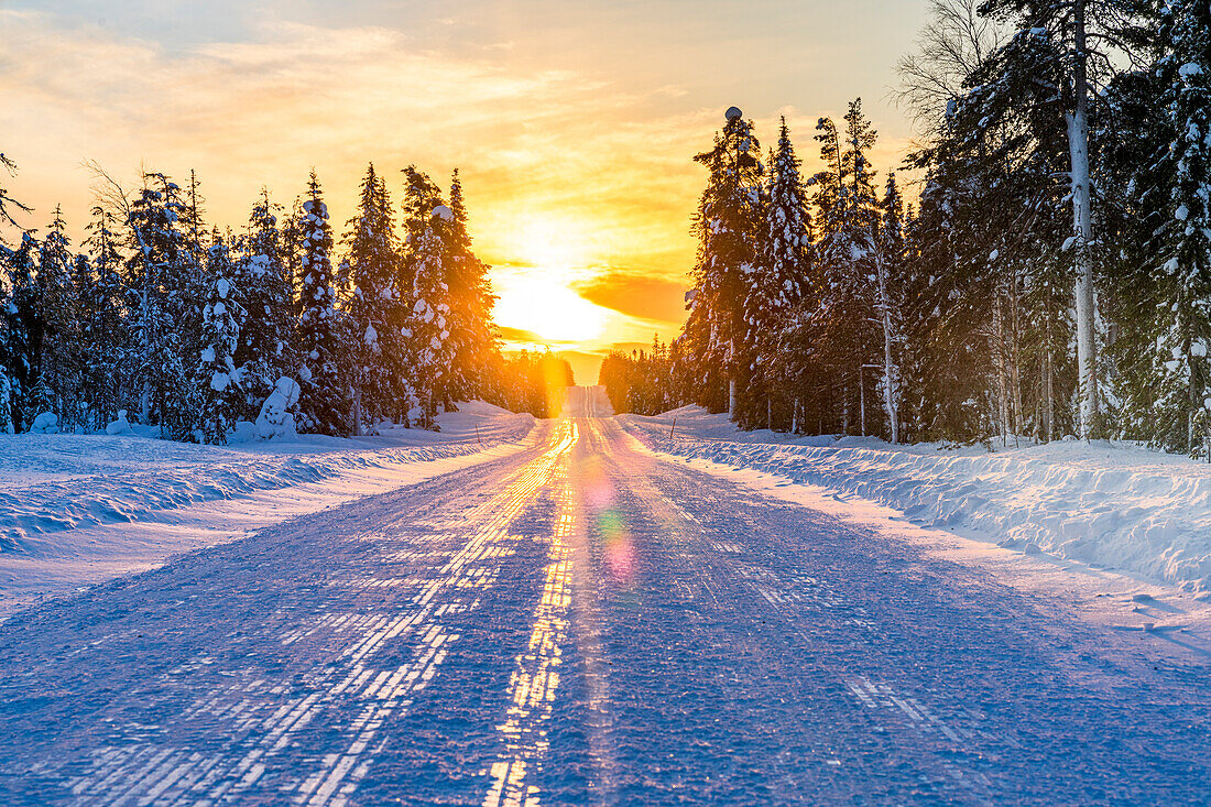 Sunset over an empty snowy road, Lapland, Finland, Europe