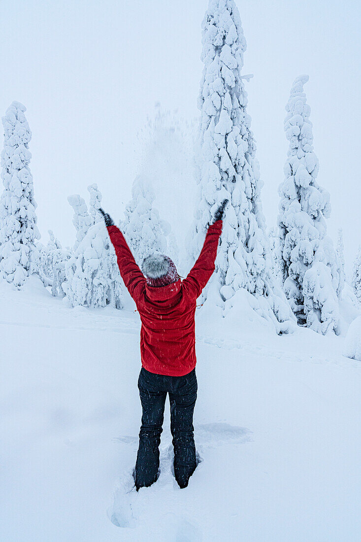 Fröhliche Frau mit ausgestreckten Armen spielt mit Schnee, Lappland, Finnland, Europa