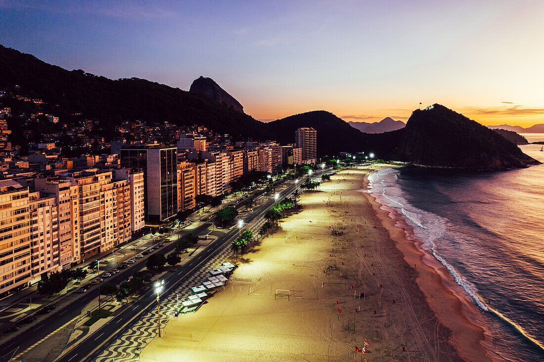 Drohnenaufnahme des Leme Beach im Copacabana-Viertel bei Sonnenaufgang mit dem berühmten Zuckerhut im Hintergrund, UNESCO-Weltkulturerbe, Rio de Janeiro, Brasilien, Südamerika