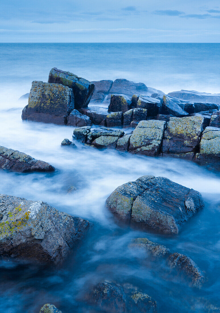 Felsen und Summer Isles im Hintergrund während der dramatischen blauen Beleuchtung in der Abenddämmerung an der Küste von Nordwest-Schottland, Highland, Schottland, Vereinigtes Königreich, Europa