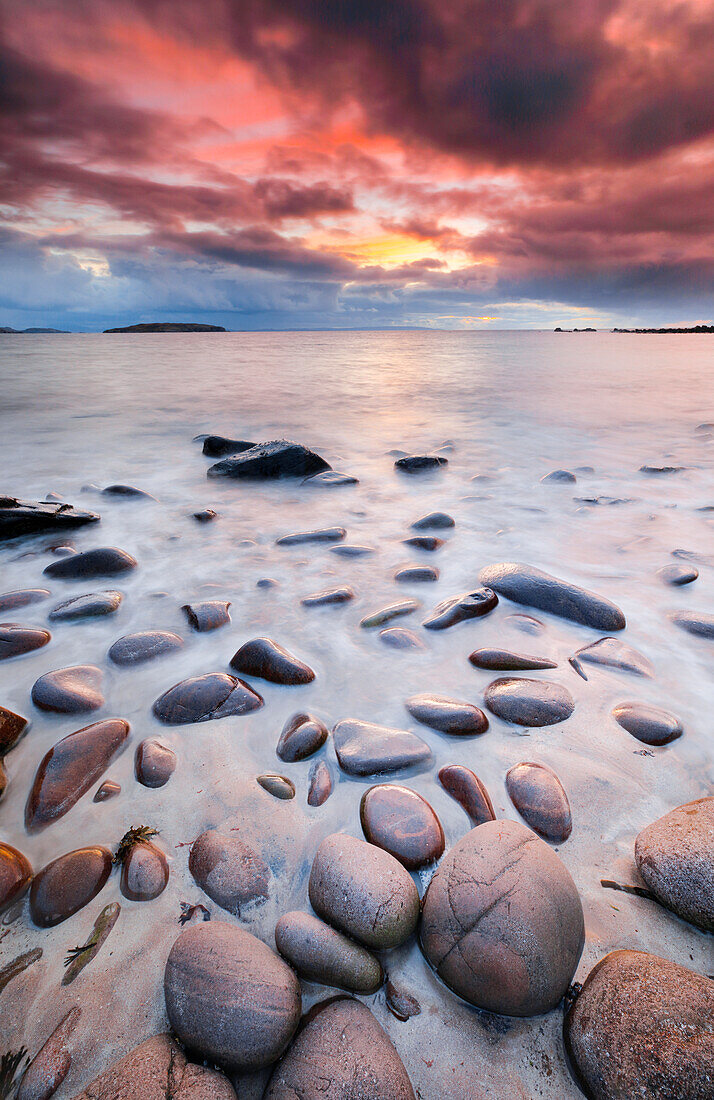 Felsen und Sandstrand an der Reiff Bay mit den Summer Isles im Hintergrund während eines farbenprächtigen Sonnenuntergangs an der Küste im Nordwesten Schottlands, Highland, Schottland, Vereinigtes Königreich, Europa
