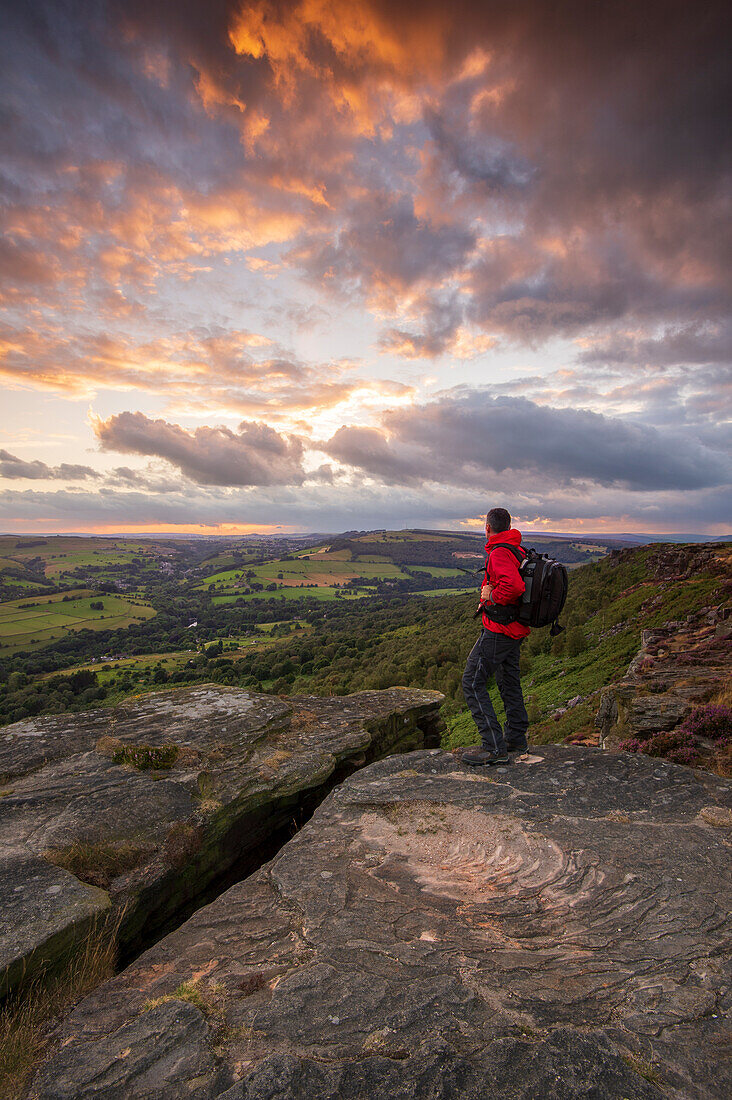 A walker standing on Curbar Edge at sunset, Derbyshire, Peak District, Derbyshire, England, United Kingdom, Europe