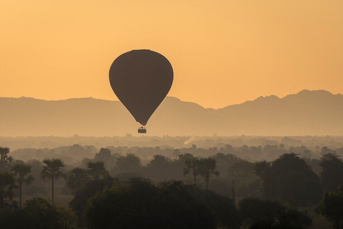 Heißluftballon bei Sonnenaufgang über den Bergen, Bagan (Pagan), Myanmar (Birma), Asien
