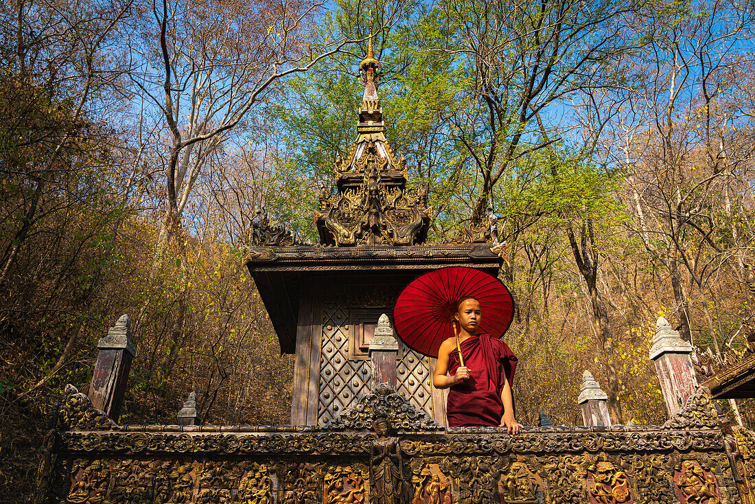 Novice monk with umbrella at monastery, Mandalay, Myanmar (Burma), Asia