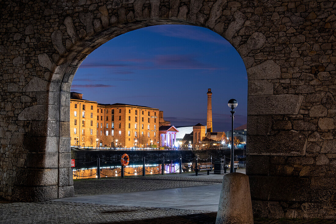 The Albert Dock and Pumphouse viewed through a remnant of the original dock wall at night, Liverpool Waterfront, Liverpool, Merseyside, England, United Kingdom, Europe