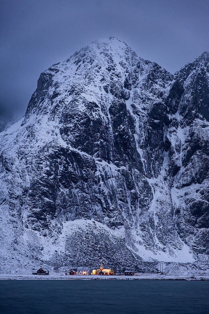 Flakstad Kirke (Flakstad Kirche) und Flakstadtind Berg über Flakstadpollen Fjord in der Nacht im Winter, Flakstad Kommune, Nordland County, Lofoten Inseln, Norwegen, Skandinavien, Europa