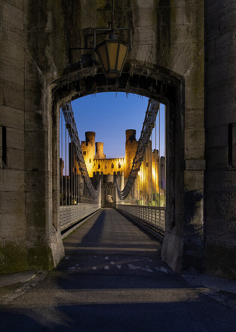 Entrance to Telford's Conwy Suspension Bridge and Conwy Castle at night, UNESCO World Heritage Site, Conwy, North Wales, United Kingdom, Europe