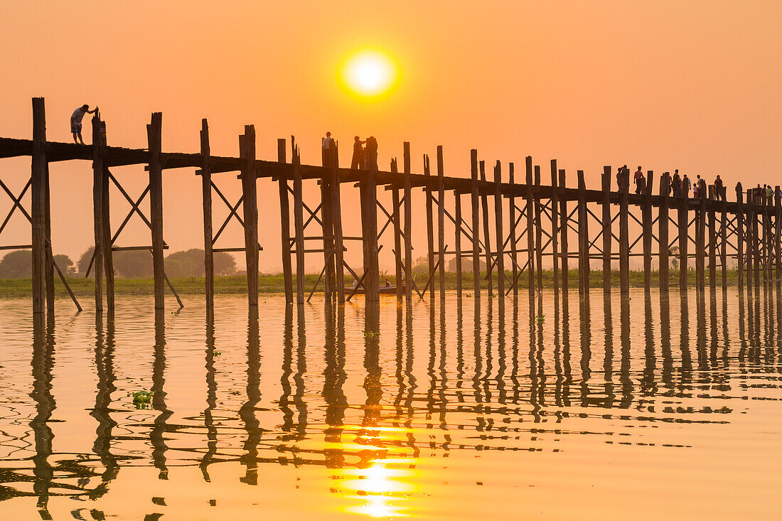 Spaziergänger auf der U-Bein-Brücke über den Taung Tha Man-See bei Sonnenuntergang, Amarapura, Mandalay, Myanmar (Burma), Asien