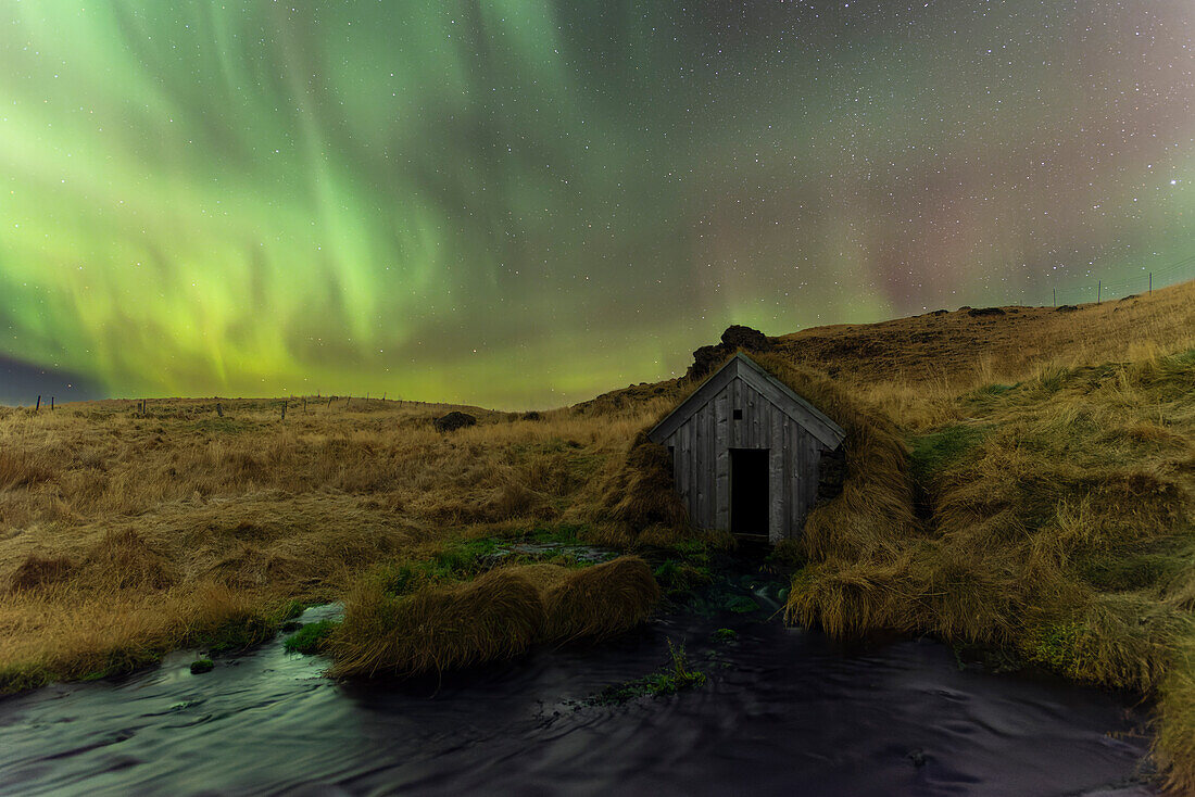 Keldur old mill turf house and hills lit by Northern Lights (Aurora Borealis), Rangarvellir, Sudurland, South Iceland, Iceland, Polar Regions