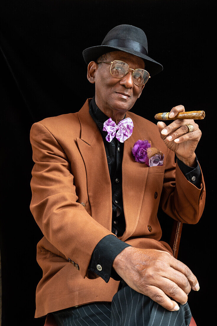 Man seated dressed as 1950s dandy or gangster with fedora hat and big cigar, Havana, Cuba, West Indies, Caribbean, Central America