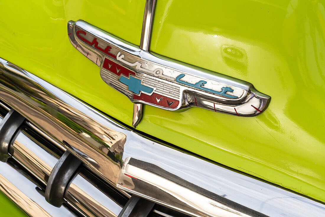 Bonnet insignia and bumper detail from green Chevrolet classic car, Havana, Cuba, West Indies, Caribbean, Central America
