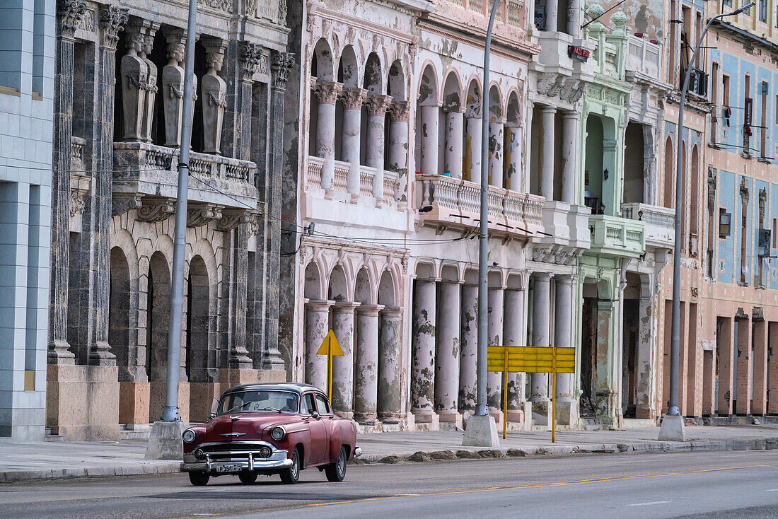 Verblasste Pracht, Stuck, verwitterte Häuser an der Uferpromenade des Malecon, mit rotem Oldtimer, Havanna, Kuba, Westindien, Karibik, Mittelamerika