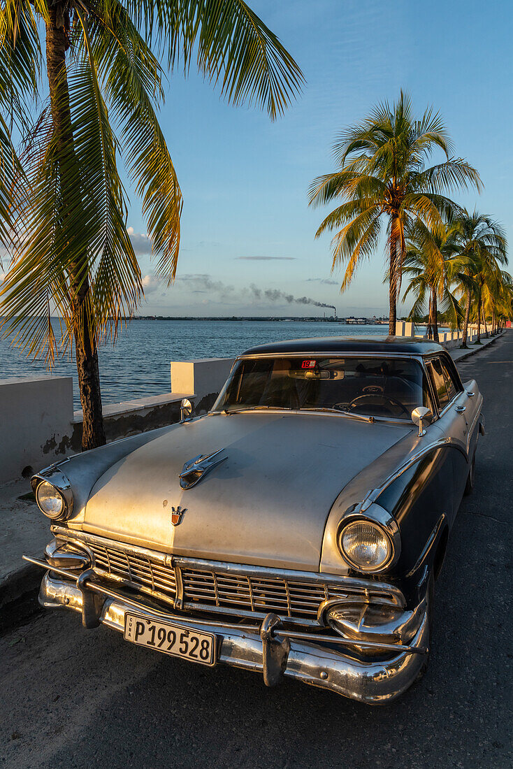 Klassischer silberner Ford auf einsamer Küstenstraße geparkt, Raffinerie im Hintergrund, Cienfuegos, Kuba, Westindische Inseln, Karibik, Mittelamerika
