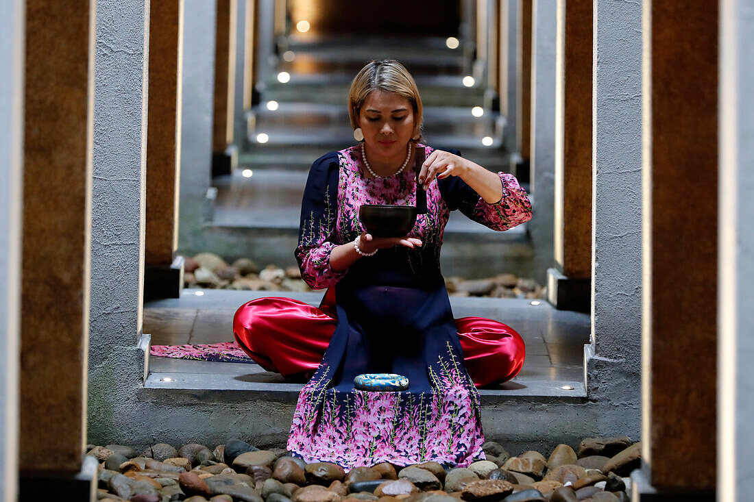Tibetische Schale, buddhistische Frau übt eine Klangschale für die Klangtherapie in einer Atmosphäre für Heilung, Meditation, Yoga und Entspannung, Quang Ninh, Vietnam, Indochina, Südostasien, Asien