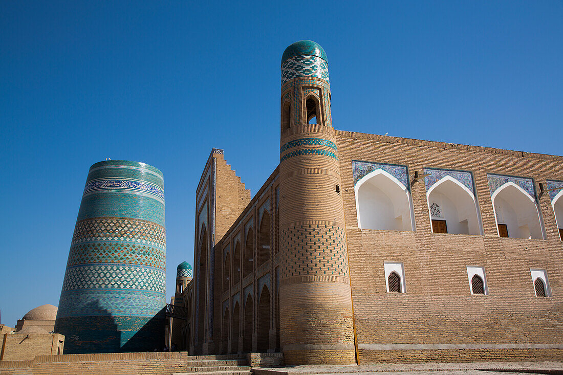 Kalta Minarett auf der linken Seite, Muhammad Amin Khan Madrasah (Orient Star Hotel) auf der rechten Seite, Ichon Qala (Itchan Kala), UNESCO-Weltkulturerbe, Chiwa, Usbekistan, Zentralasien, Asien