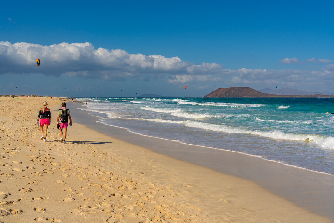 Blick auf ein Paar, das am Strand und am Atlantischen Ozean spazieren geht, Corralejo Natural Park, Fuerteventura, Kanarische Inseln, Spanien, Atlantik, Europa