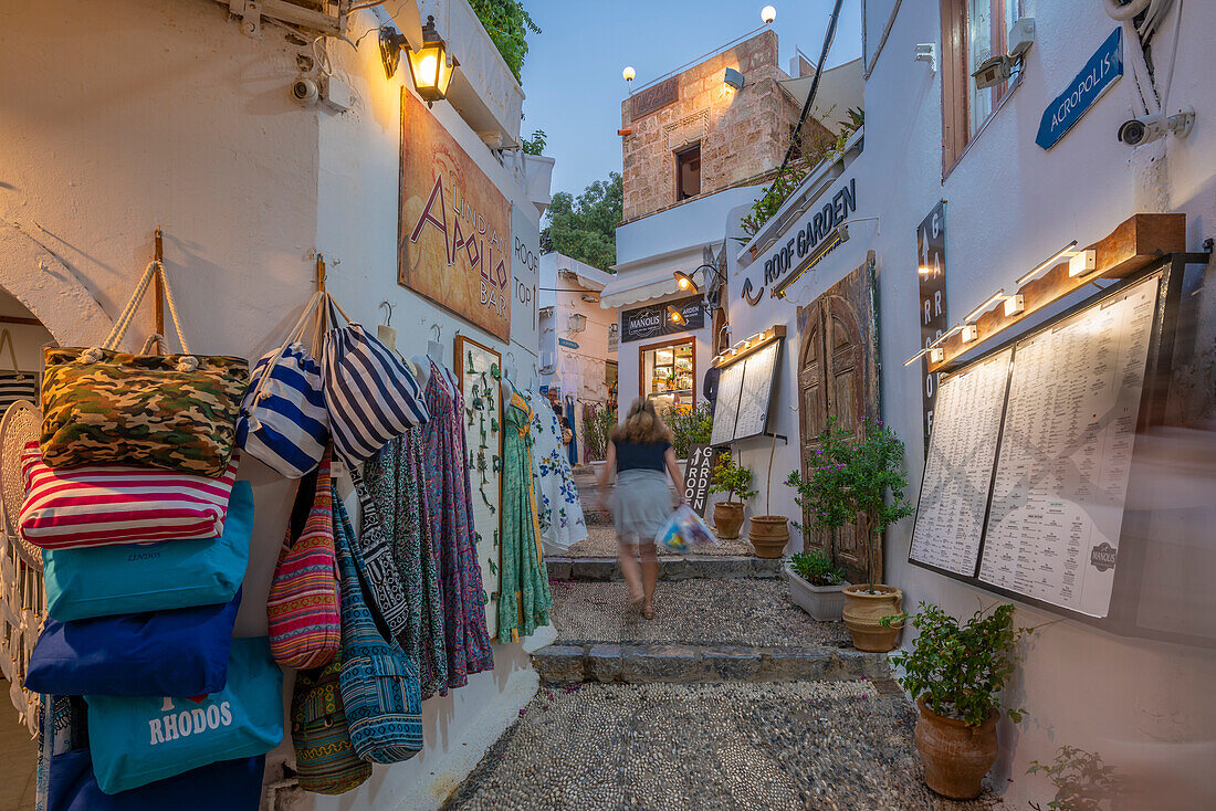 Blick auf die Geschäfte in der Straße von Lindos in der Abenddämmerung, Lindos, Rhodos, Dodekanes-Inselgruppe, Griechische Inseln, Griechenland, Europa