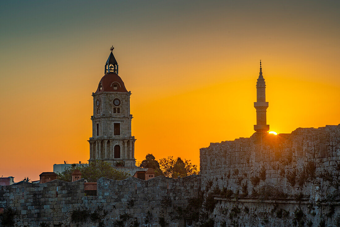 View of sunrise between Medieval Clock Tower and Mosque of Suleiman, UNESCO World Heritage Site, Rhodes Town, Rhodes, Dodecanese Island Group, Greek Islands, Greece, Europe