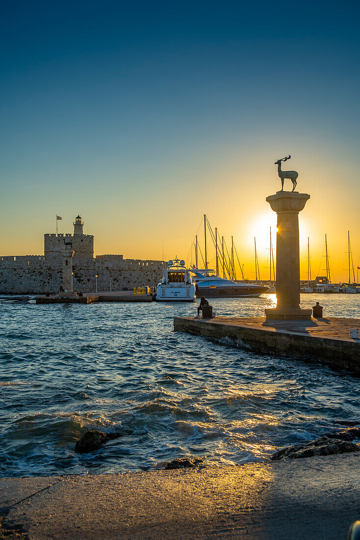 Blick auf bronzene Hirsch- und Rehstatuen und die Festung des Heiligen Nikolaus bei Sonnenaufgang, UNESCO-Weltkulturerbe, Stadt Rhodos, Rhodos, Dodekanes-Inseln, Griechische Inseln, Griechenland, Europa