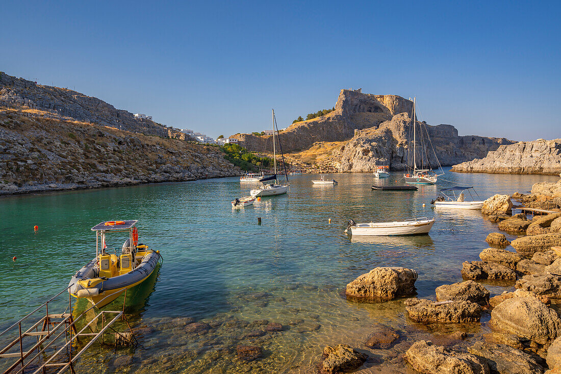 View of sailboats in St. Paul's Bay, Lindos, and Lindos Acropolis from beach, Lindos, Rhodes, Dodecanese Island Group, Greek Islands, Greece, Europe