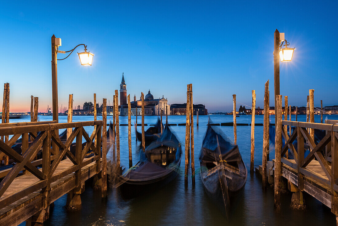 The venetian gondolas moored at Riva degli Schiavoni and in background St. George's church during sunrise, Venice, Veneto, Italy, Europe