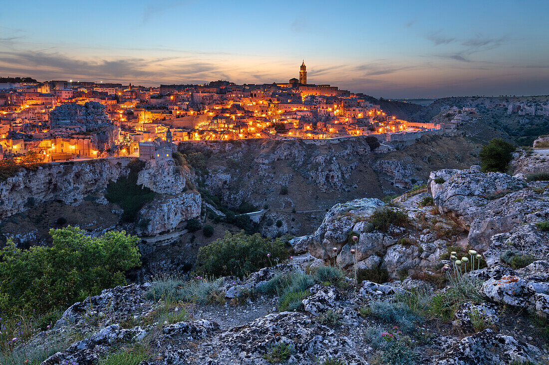 Dusk over the Gravina River canyon and the floodlit Sassi di Matera old town, UNESCO World Heritage Site, Matera, Basilicata, Italy, Europe