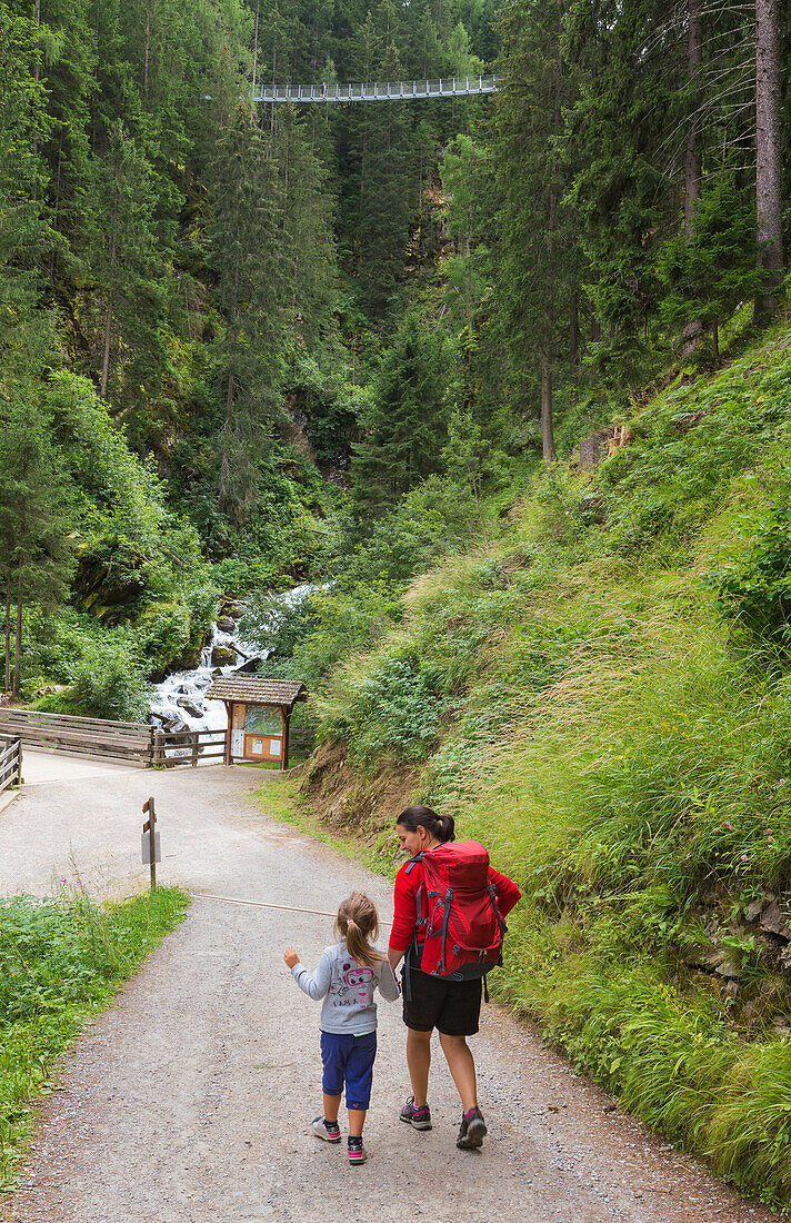 Mom and daughter walk on the path to reach the tibetan bridge (Ponte Sospeso Ragaiolo), Rabbi valley (val di Rabbi), Trento province, Trentino-Alto Adige, Italy, Europe (MR)