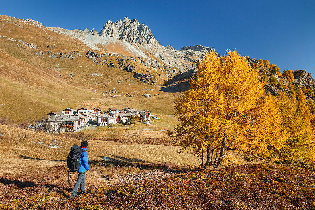 Wanderer schaut auf ein kleines Dorf während einer Herbstwanderung, Engadin, Silser See, Kanton Graubünden, Schweiz, Europa (MR)