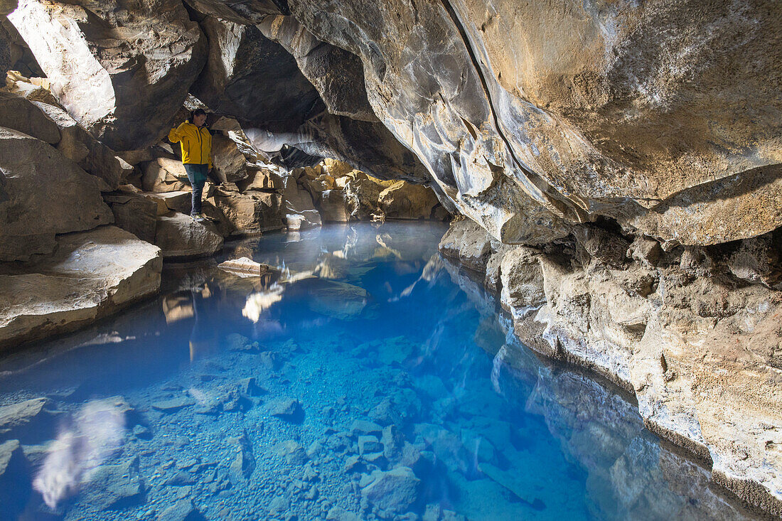 Ein Tourist bewundert den unterirdischen Fluss in der Grjótagjá-Höhle, in der Nähe des Mivathn-Sees, Norduland, Mivathn, Ostisland, Island, Europa.