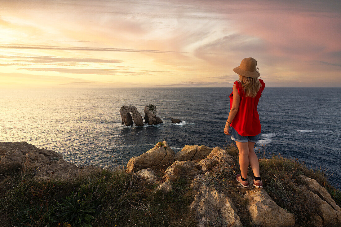 ein Tourist genießt den sommerlichen Sonnenuntergang in der Nähe der Manzano-Felsen, Bajos de Arnia, Kantabrien, Spanien, Iberische Halbinsel, Westeuropa