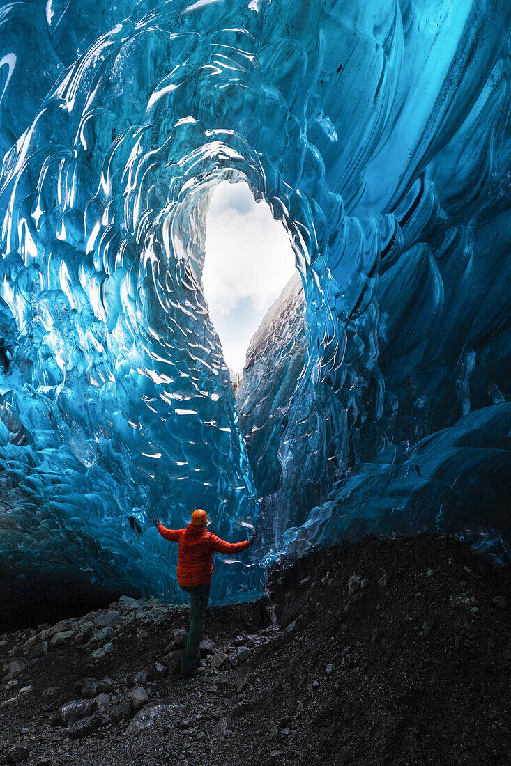 Ein Wanderer bewundert eine Eishöhle in der Jokusarlon Glacier Lagoon Region im Winter, Austurland, Island, Europa