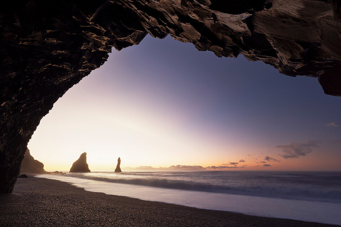 the stacks of Vik i Myrdal, seen from an sea cave during a winter sunrise, Reynisfjara beach, southern Iceland, Europe