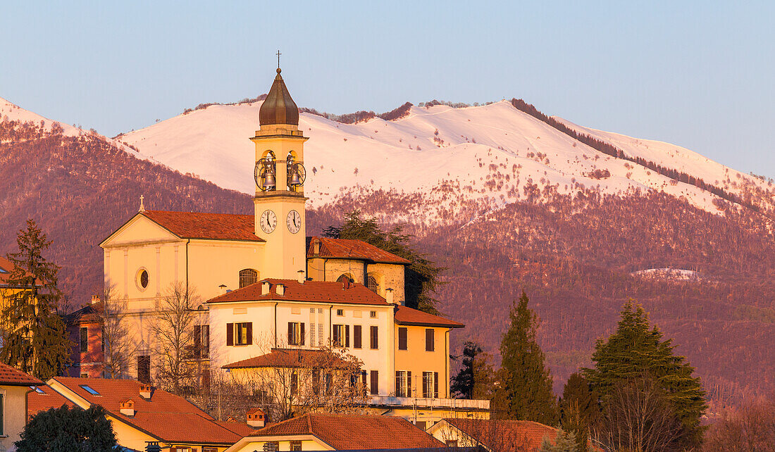 Sunset on the church of SS Cosma e Damiano, Bollettone mount snowy in the background, Civello village, Villa Guardia, Brianza, Como province, Lombardy, Italy, Europe